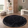 A round black shaggy rug is placed on a wooden floor in a living room setting, next to a ladder shelf and a plant. Anteprima dell’immagine prodotto
