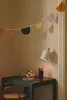 A child's desk area with a wall lamp, a garland, and art supplies. Voir les images du produit