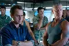 A group of men in a control room or similar indoor setting. Produktbild-Vorschau