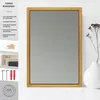 A gold-framed mirror is displayed on a white surface next to a white vase with dried flowers. Produktbild-Vorschau
