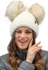 A woman wearing a white winter hat with two pom-poms and a gray jacket. Produktbild-Vorschau