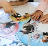 Children's hands are assembling a puzzle featuring characters from Disney's Frozen II. Produktbild-Vorschau