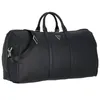 A black duffel bag with a shoulder strap and handles, featuring a triangular Guess logo. Produktbild-Vorschau