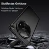 A black smartphone case with a carbon fiber accent is shown at an angle, appearing to be dropped onto a rocky surface. The background is dark and textured. Produktbild-Vorschau
