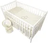 A white crib with baby bedding and a swaddled baby. Náhled obrázku produktu