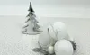 A silver Christmas tree decoration and several white Christmas ornaments are arranged on a patterned surface. Anteprima dell’immagine prodotto