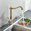 A vintage-style kitchen faucet is shown in use, with water running into a sink containing a colander of fresh vegetables. Náhľad obrázku produktu