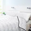 A white bed with pillows and a comforter. Náhľad obrázku produktu