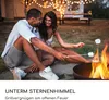 A couple roasting marshmallows over a fire pit in a backyard at night. Produktbild-Vorschau