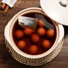 A close-up overhead view of a pot of tea-infused eggs, with a tea bag steeping in the liquid. Produktbild-Vorschau