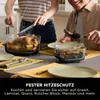 Two people are preparing to serve a roasted chicken and asparagus from glass cooking dishes on a table. Anteprima dell’immagine prodotto