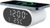 A white digital alarm clock with a wireless charging pad on top, charging a smartphone. The clock displays the time and temperature. Produktbild-Vorschau