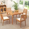 A wooden dining set with chairs and a table in a room with a window overlooking a garden. Produktbild-Vorschau