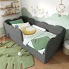 A child's bedroom with a gray upholstered bed, green rug, and cloud-themed wall art. Produktbild-Vorschau