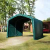 A green tarp shelter in a rural outdoor setting with trees and farm buildings. Voir les images du produit