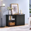 A black wooden sideboard with sliding doors and open shelves, decorated with vases, books, and a framed picture, placed in a room with a blue wall and a floor lamp. Produktbild-Vorschau