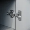 A close-up view of a cabinet hinge attached to a gray cabinet door. Produktbild-Vorschau