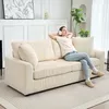 A woman is relaxing on a cream-colored corduroy sofa, wearing headphones. Náhľad obrázku produktu