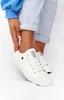A close-up shot of a person's feet wearing white low-top sneakers. Podgląd zdjęcia produktu