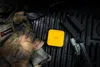 Tactical gear, including gloves, a tactical vest, magazines, a handgun, and a yellow power bank, laid out on a textured black surface. Produktbild-Vorschau