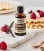 A bottle of vanilla extract is placed on a marble board with waffles, raspberries, and vanilla beans. Náhled obrázku produktu