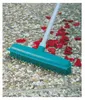 A teal rubber broom with a gray handle is shown on a textured outdoor surface with scattered red rose petals. Produktbild-Vorschau