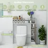 A bathroom scene featuring a toilet with an over-the-toilet storage unit, decorated with plants and toiletries. Voir les images du produit