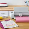 A crafting setup with a cutting machine, heat press, and t-shirts. Produktbild-Vorschau