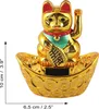 A golden lucky cat figurine sits on a boat-shaped base adorned with coins. The cat has its paw raised in a waving gesture. Dimensions are indicated by measurement lines. Produktbild-Vorschau