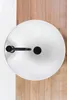 A top-down view of a white round sink with black fixtures, placed on a wooden floor. Podgląd zdjęcia produktu