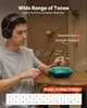 A man wearing headphones plays a steel tongue drum on a table, with musical notes depicted in the air. Podgląd zdjęcia produktu