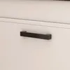 A close-up view of a black drawer pull on a white cabinet. Podgląd zdjęcia produktu
