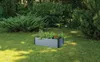 A raised garden bed filled with plants sits on a grassy lawn surrounded by trees and bushes. Náhľad obrázku produktu