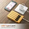 A wooden knife block with knives inserted is shown, with a smartphone and a white USB charger nearby, on a wooden table. Podgląd zdjęcia produktu