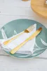 A place setting with a plate, napkin, fork, and knife on a white wooden table. Anteprima dell’immagine prodotto