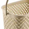 A close-up view of the top edge and handle attachment of a beige laundry basket with a perforated design. Podgląd zdjęcia produktu