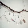 A handmade heart ornament made of wire and paper, hanging from a branch. Produktbild-Vorschau