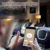 A person is holding a smartphone with a smart thermostat app open, while sitting in a car. The smart thermostat is visible on the wall in the background. Podgląd zdjęcia produktu
