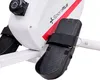 A close-up shot of the pedals and part of the main body of a white and red rowing machine. Produktbild-Vorschau