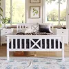 A white wooden bed with pillows and blankets is set up in a bedroom with large windows overlooking a garden. Produktbild-Vorschau
