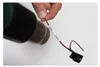 A hand holds a wire with a label and a switch attached to it, with a dark object in the background. Anteprima dell’immagine prodotto