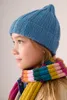 A young girl wearing a blue knitted hat and a colorful striped scarf. Produktbild-Vorschau