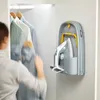 A person is reaching for a shirt in a closet, next to a wall-mounted ironing board with an iron. Náhľad obrázku produktu