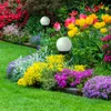 A vibrant garden bed filled with colorful flowers and two solar-powered garden lights. Produktbild-Vorschau