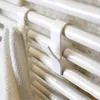 A close-up shot of white plastic hooks attached to a white radiator, with a white towel hanging on one of the hooks. Produktbild-Vorschau