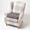 A grey seat cushion is placed on a plaid armchair. Náhled obrázku produktu