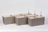 Several self-watering planters arranged in a row on a plain background. Náhled obrázku produktu