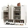 A white shoe cabinet with multiple doors and shelves, displaying various shoes and accessories. Anteprima dell’immagine prodotto