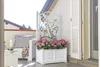 A balcony with white furniture, a planter filled with pink and green flowers, and a white trellis. Podgląd zdjęcia produktu