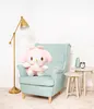 A plush toy sits on a chair next to a lamp and side tables. Podgląd zdjęcia produktu